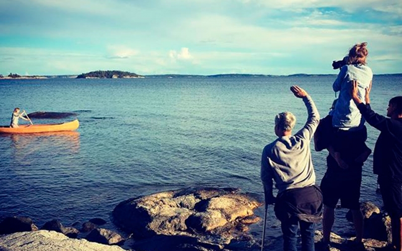 Professional outdoor photographer, Jessica Zumpfe, sitting on her assistants shoulders to get a higher perspective while shooting a girl in a canoe on the ocean.