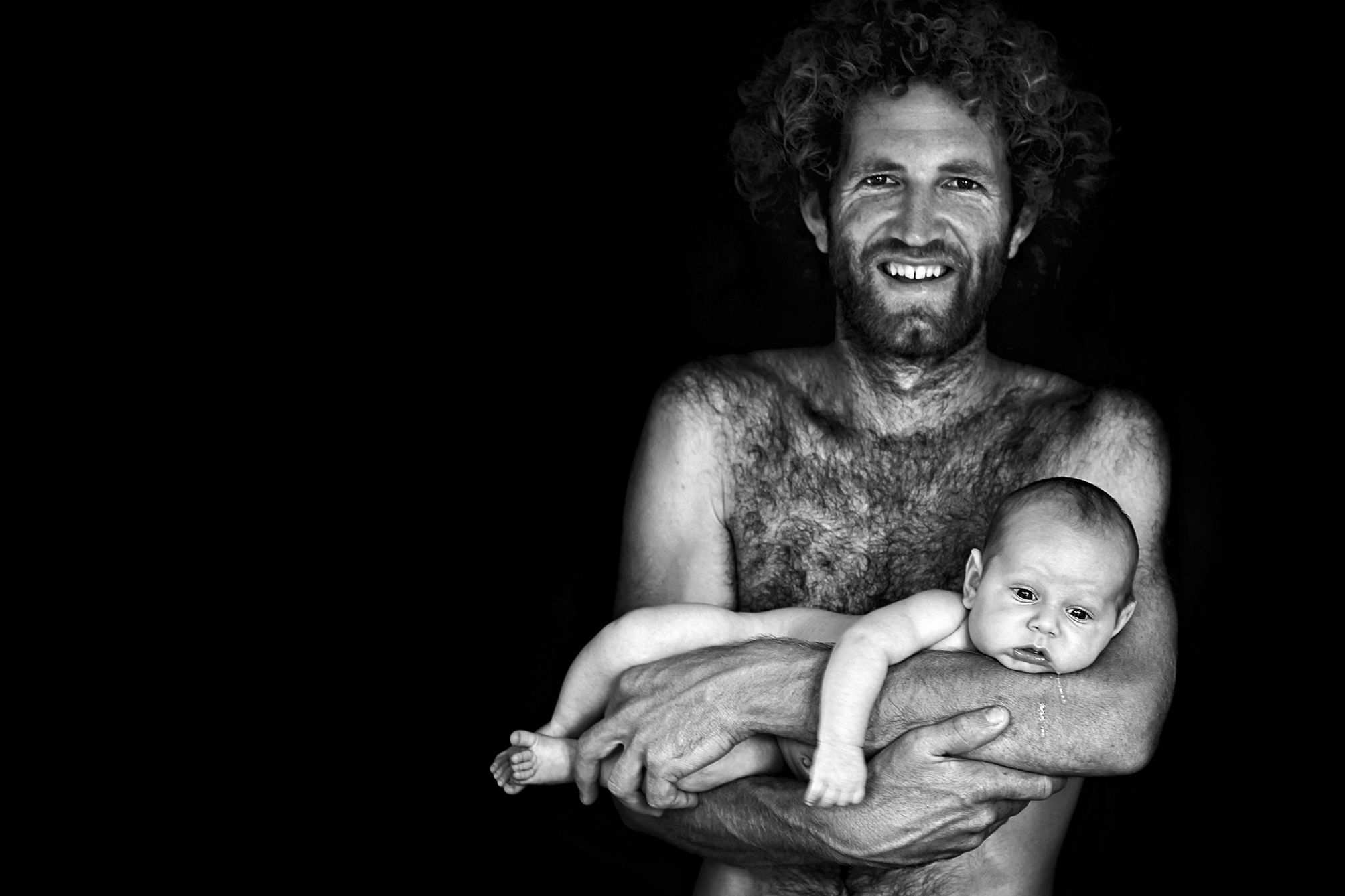 Black and white portrait of a naked man with his naked newborn