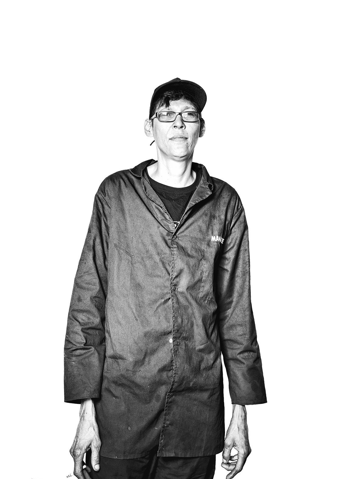 Black and white portrait of a mechanic in his working clothes, wearing a cap and glasses.