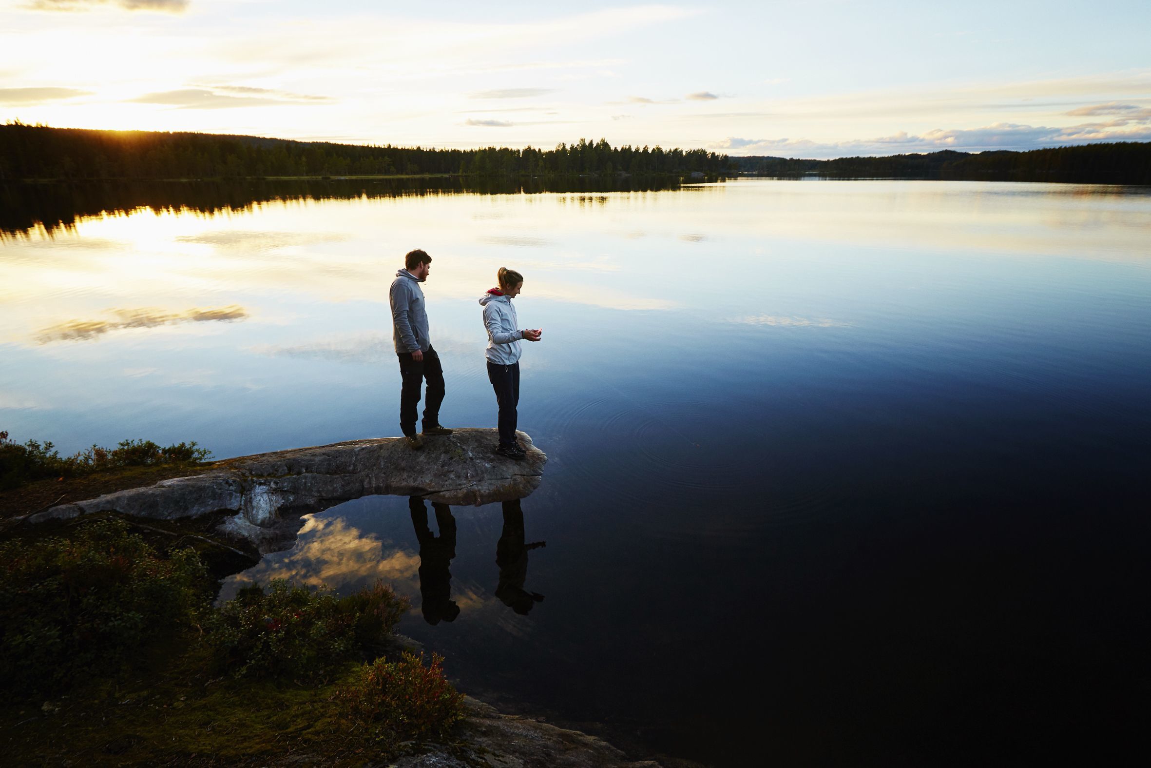 Couple fishing by a lake at sunset in Norway