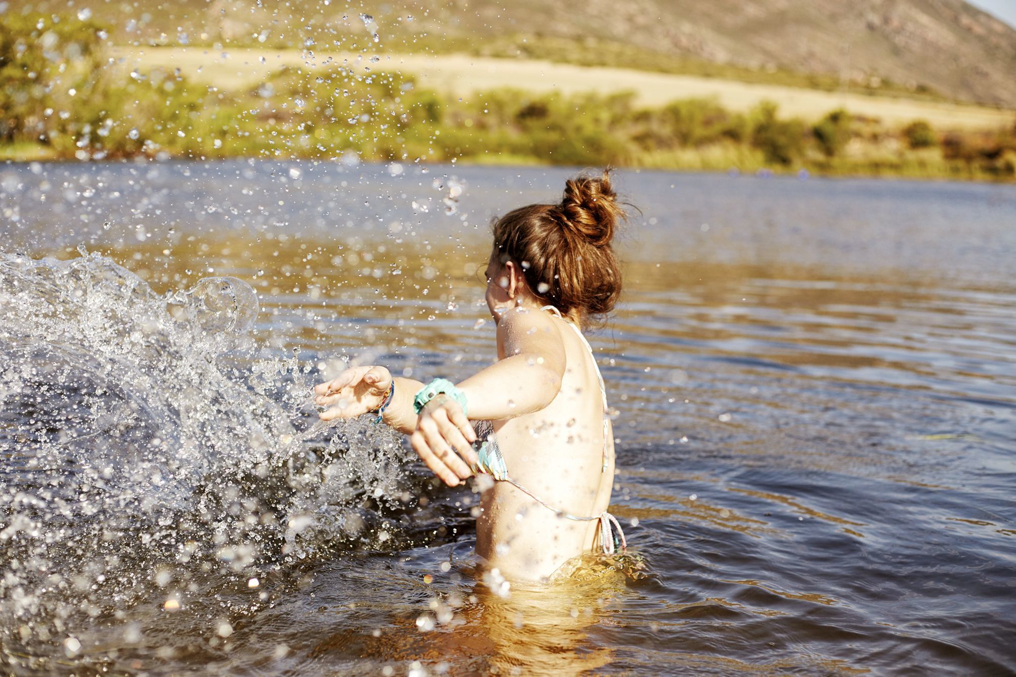 Girl bathing in a dam in South Africa splashing the photographer witth water
