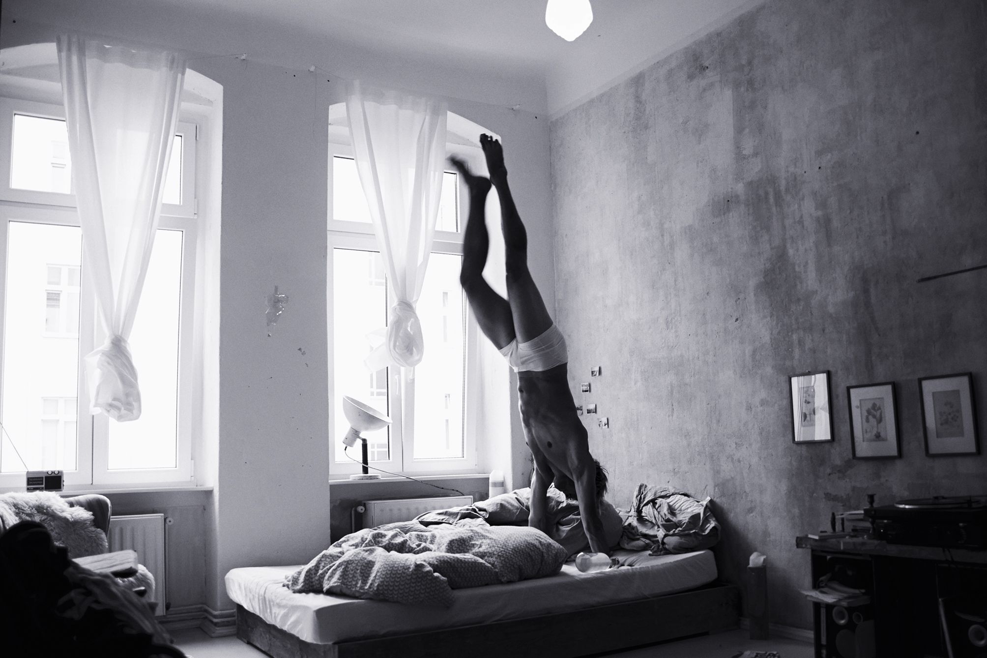 Portrait of an athlete doing handstands in his bed in Berlin