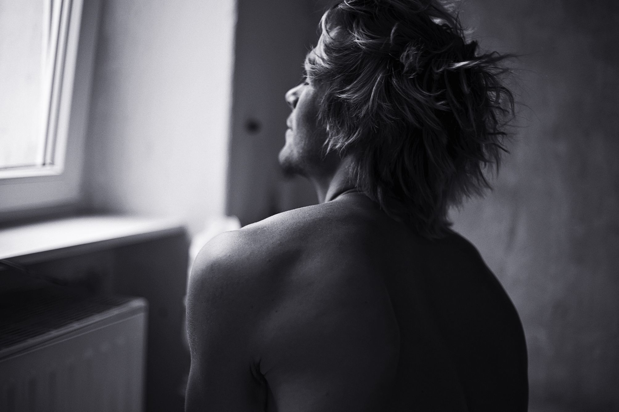 Portrait of a young athlete looking out of the window of his flat in Berlin