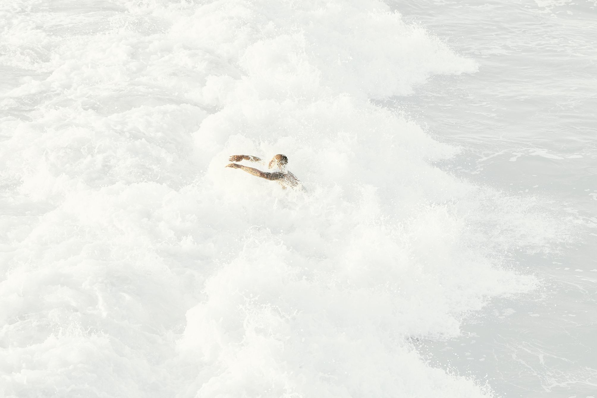 Man diving into the white wash of a wave in california.