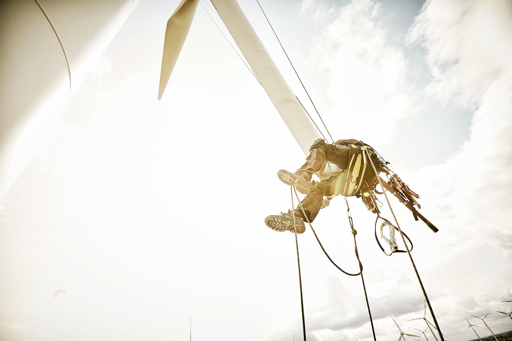 Industrial climbing shoot, here the mechanic is hanging at the bottom of a rotor blade which he has just abseiled down to check it for damages.