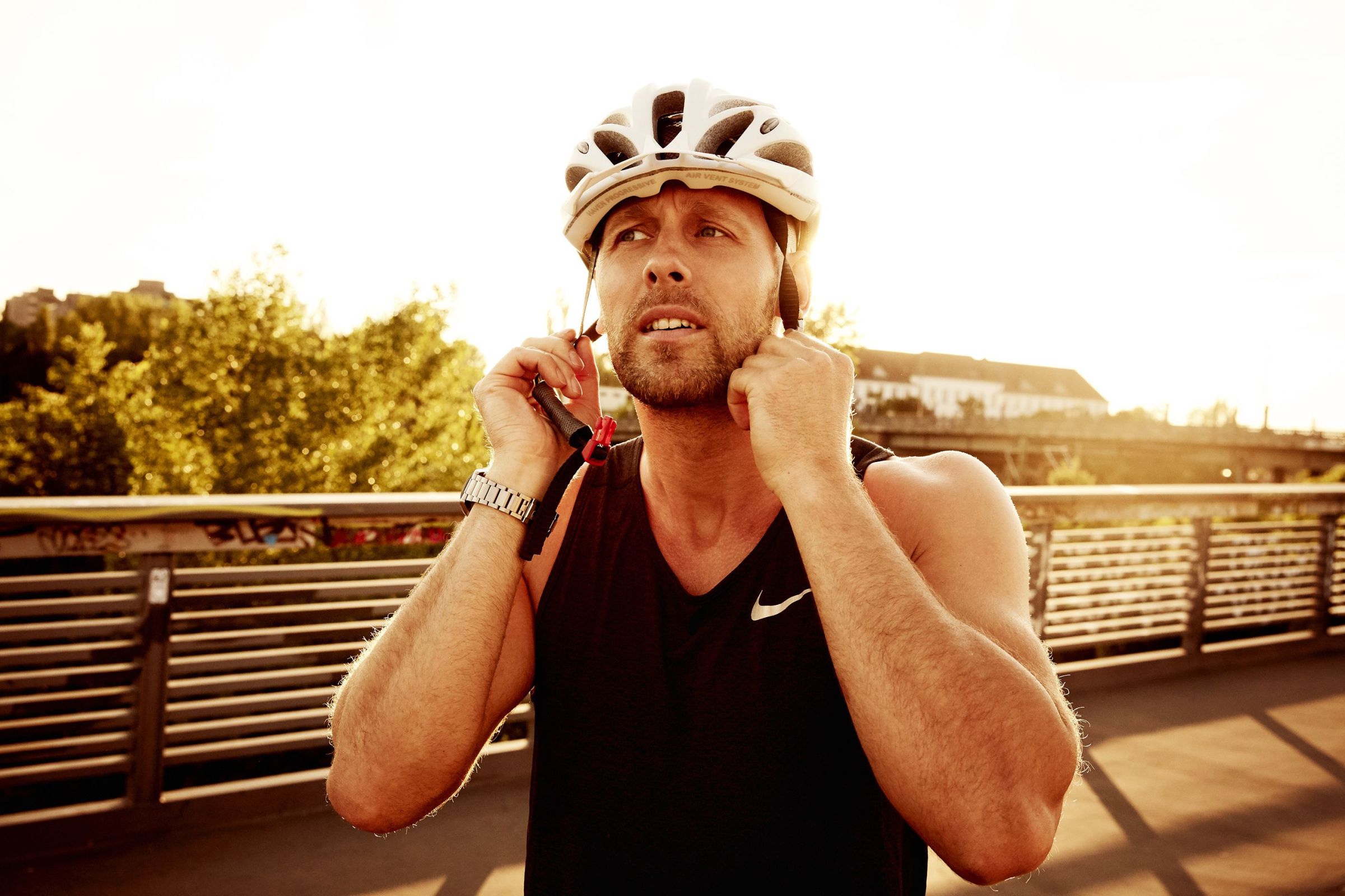 Urban sports biker putting on his biking helmet before going on a bike ride on his urban sports bike.