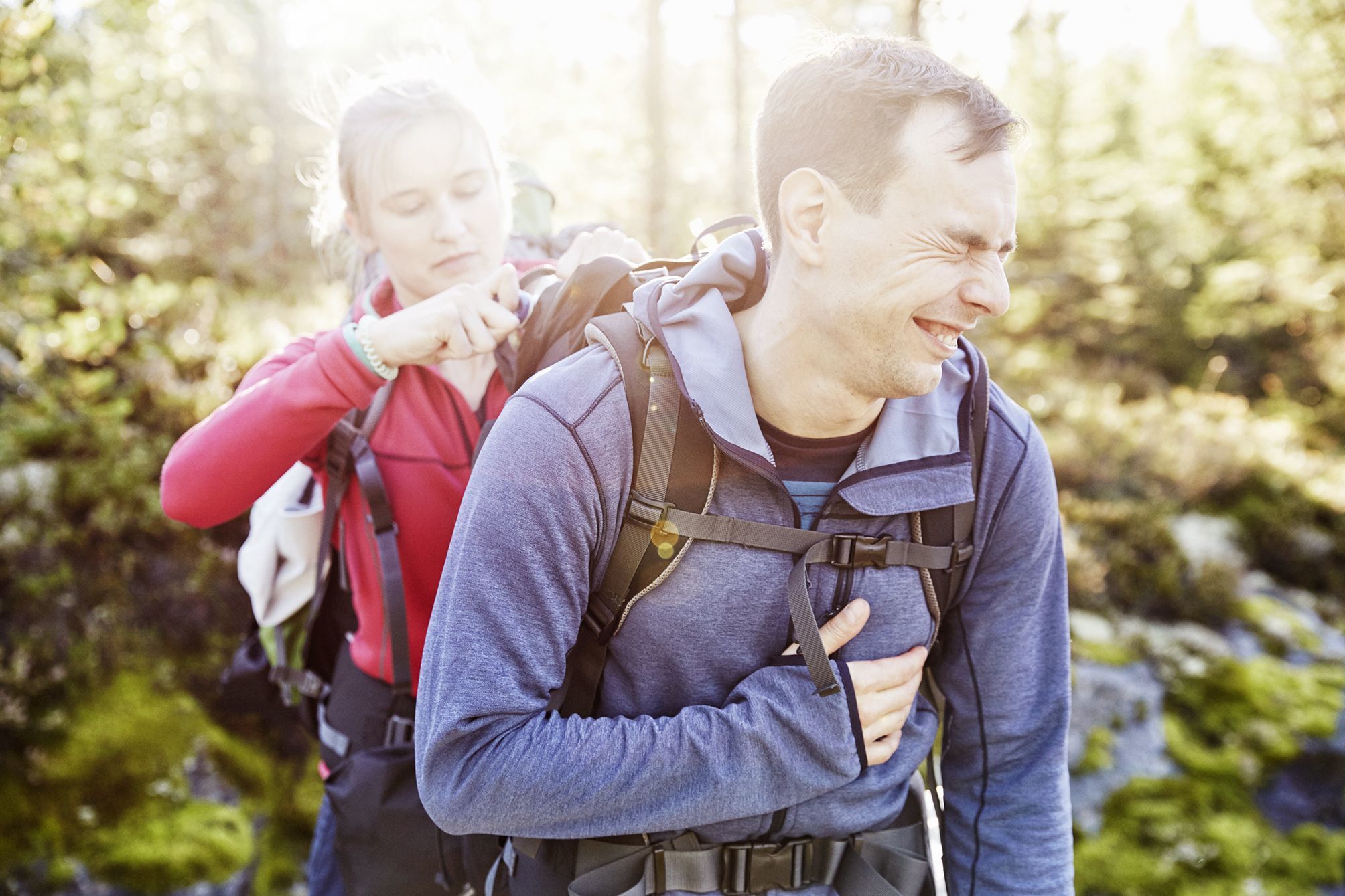 Girl packing the waterbottle in the man's backpack while on a hike in the woods in Norway during our expedition. The Man is enjoying himself.