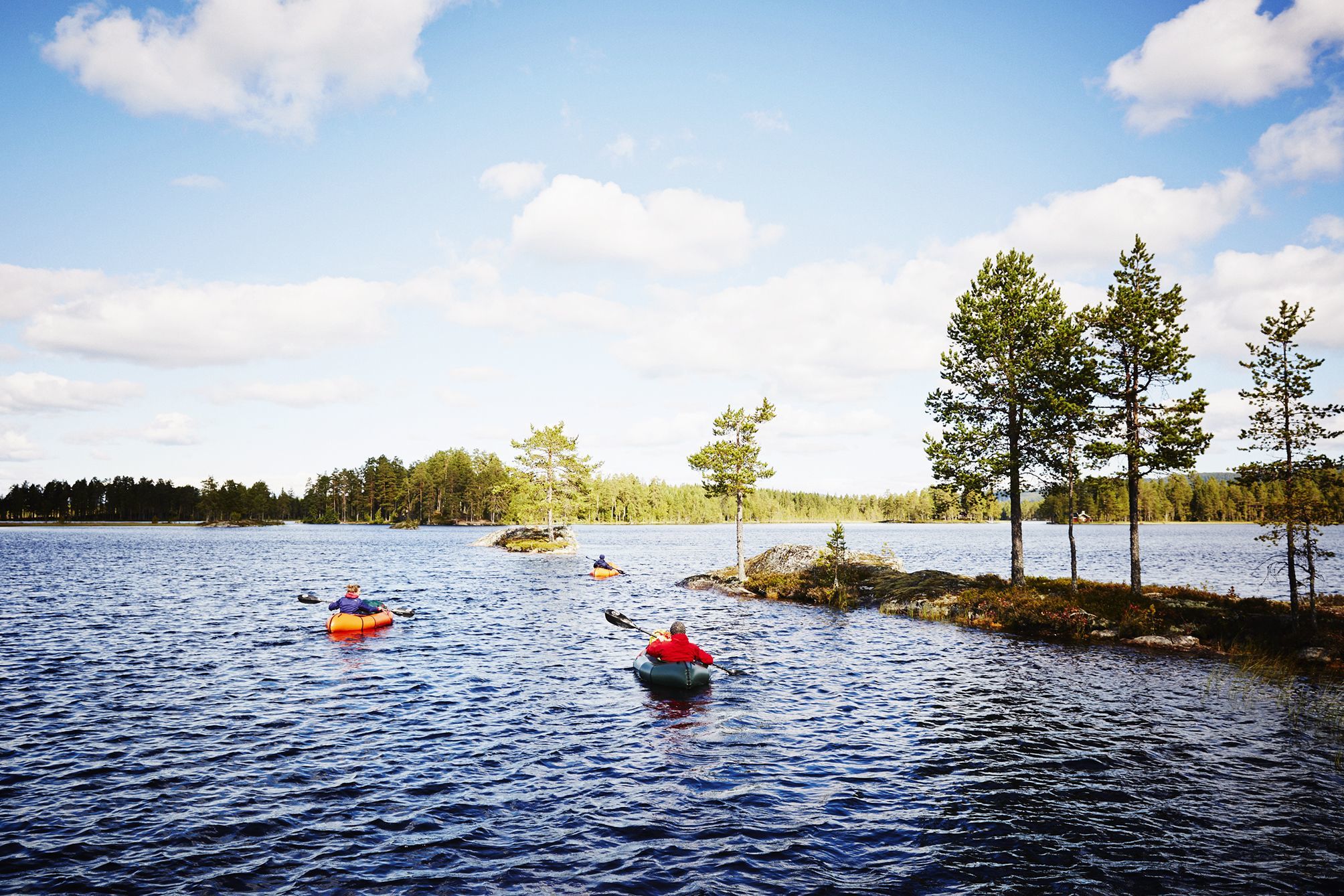 Group of packrafters navigating around islands in a lake district near Oslo, Norway