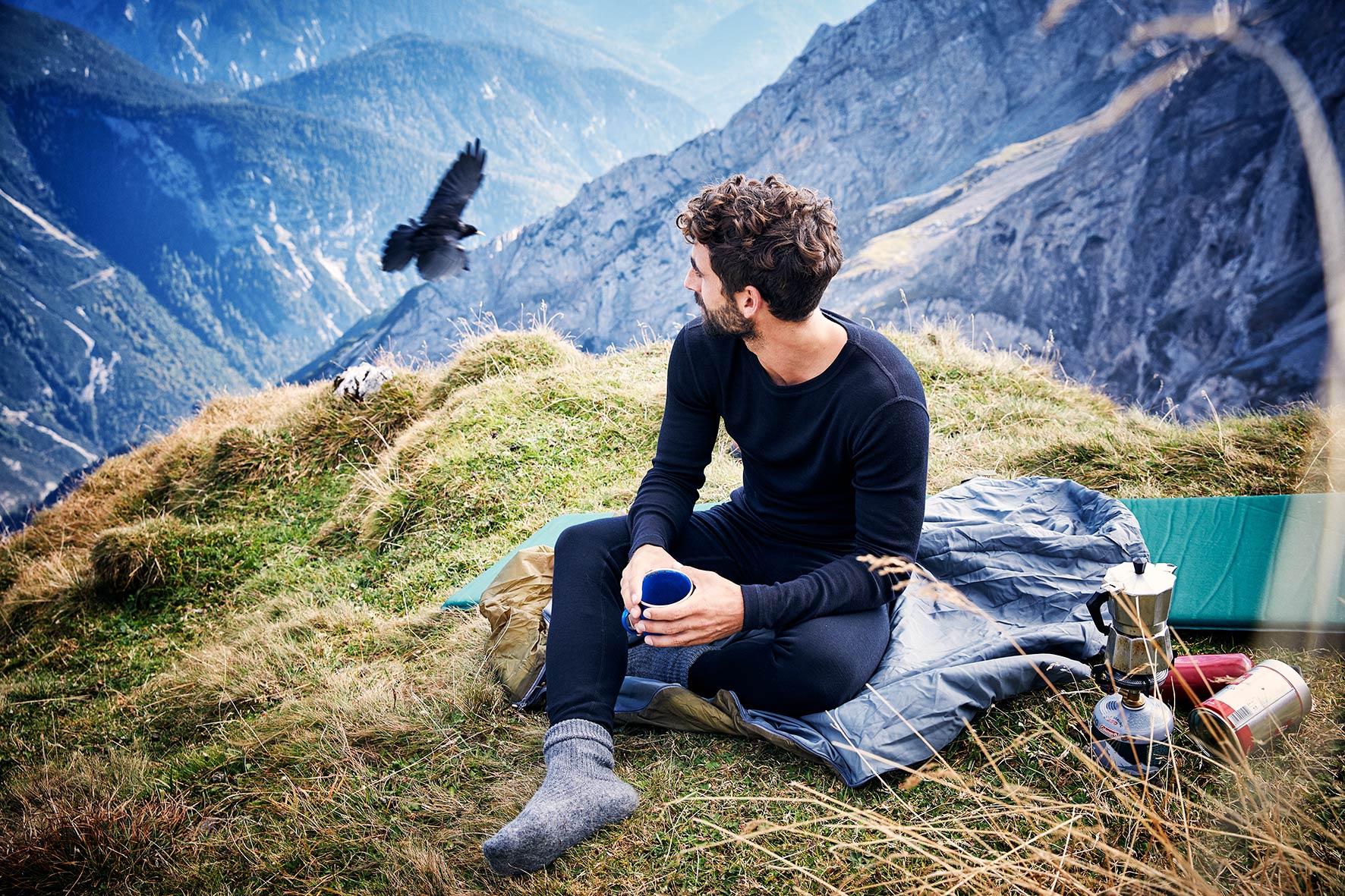 young man relaxing on a mountain while wearing sustainable fashion sports wear