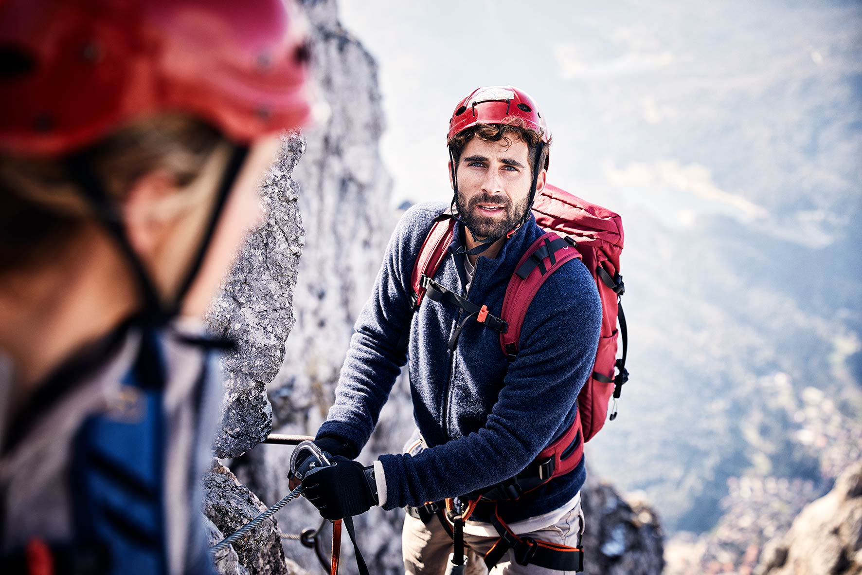 Young Man climbing a fixed rope route while wearing a helmet in the austrian alps