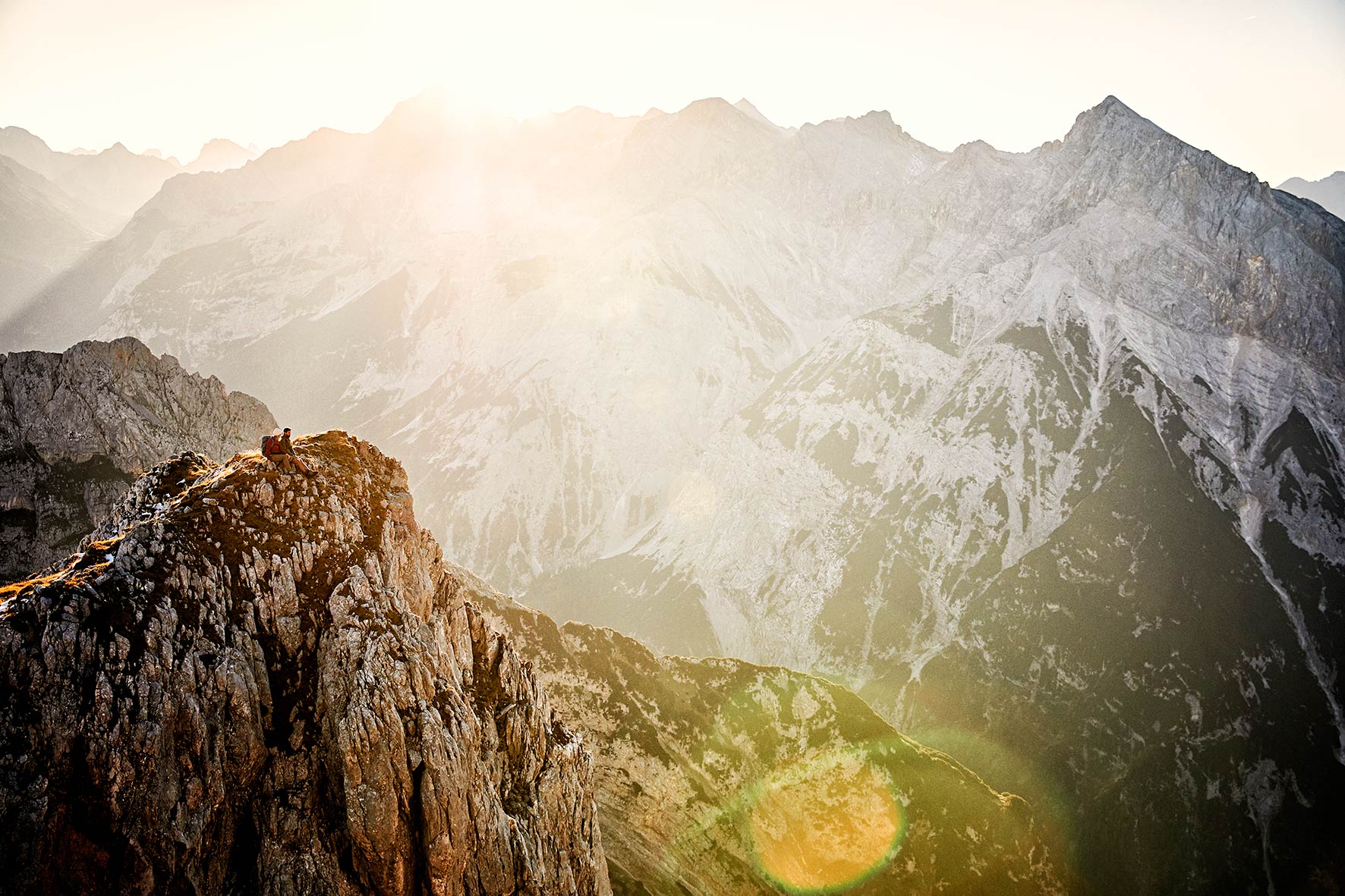 Magnificent sunrise in the mountains with a couple lost on a very steep ridge overlooking the mountains.