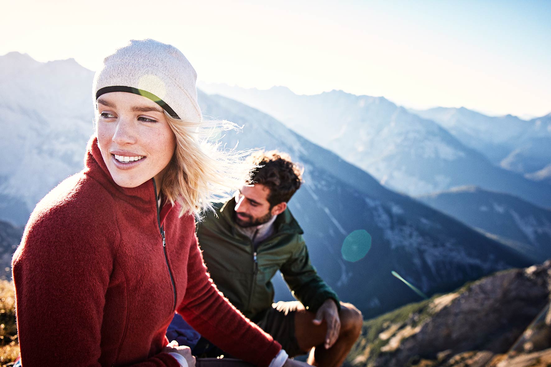 Gipfelstürmer. Portrait of a couple on top of the Karwendel mountain range at sunrise, with some lensflare and dark mountains in the background.