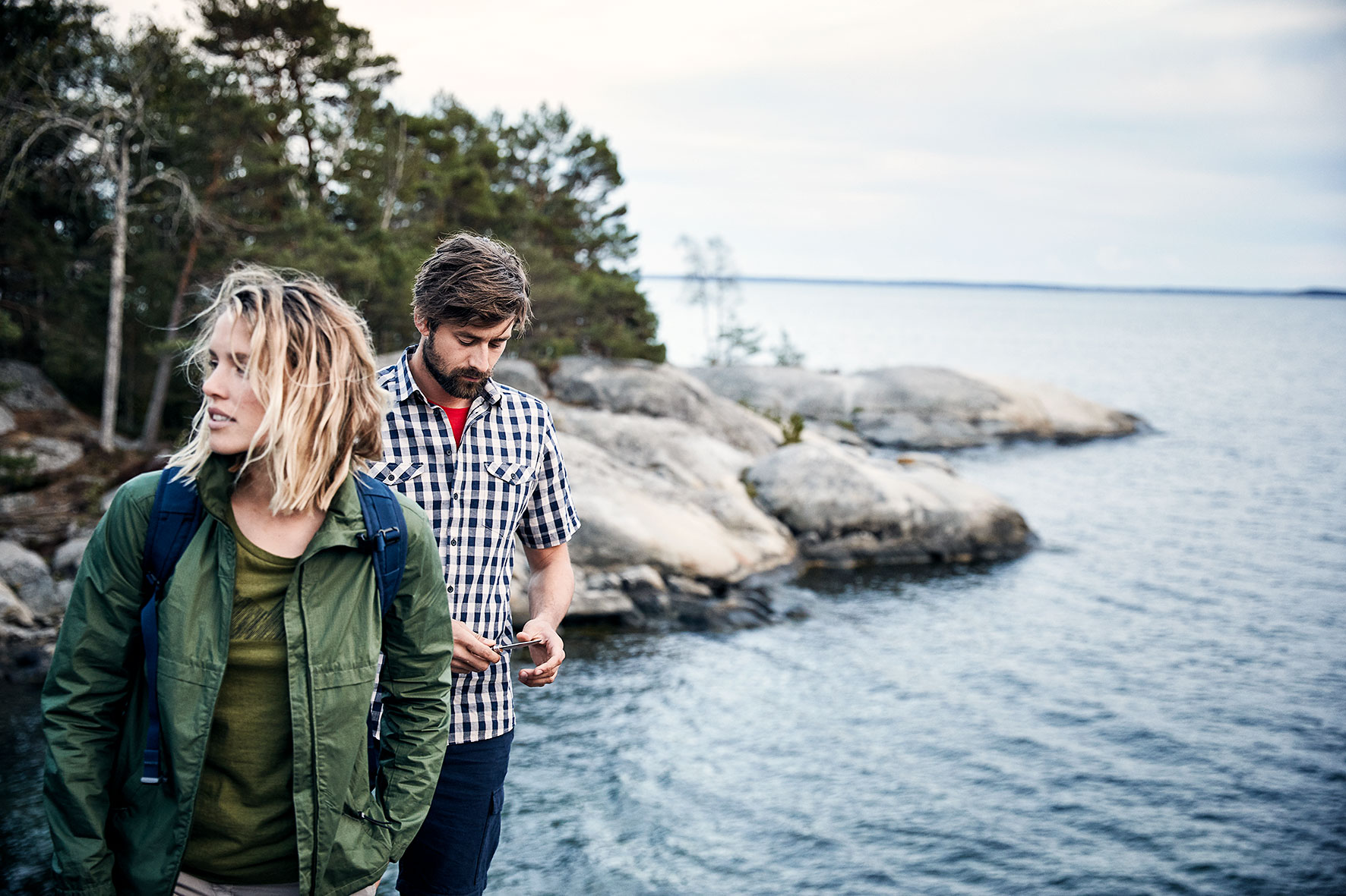 Couple standing on a cliff overlooking the sea near stockolm, Sweden. They are wearing outdoor clothing by a fair fashion brand Hess Natur