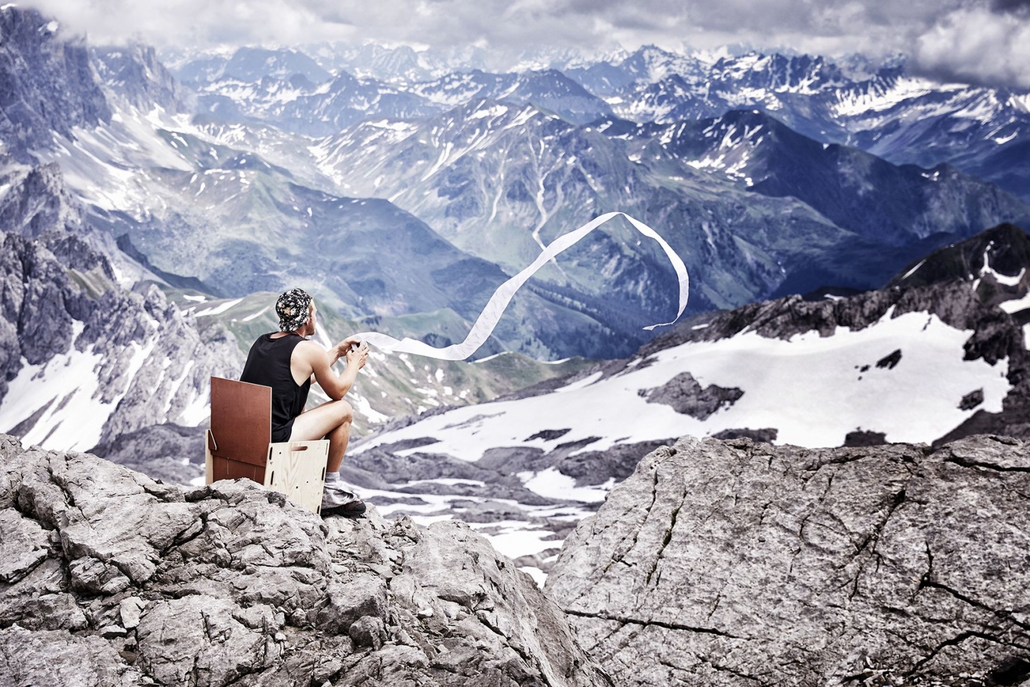 Landscape picture of a man sitting on on the top of the Schesaplana glacier with toilet paper flowing in the wind
