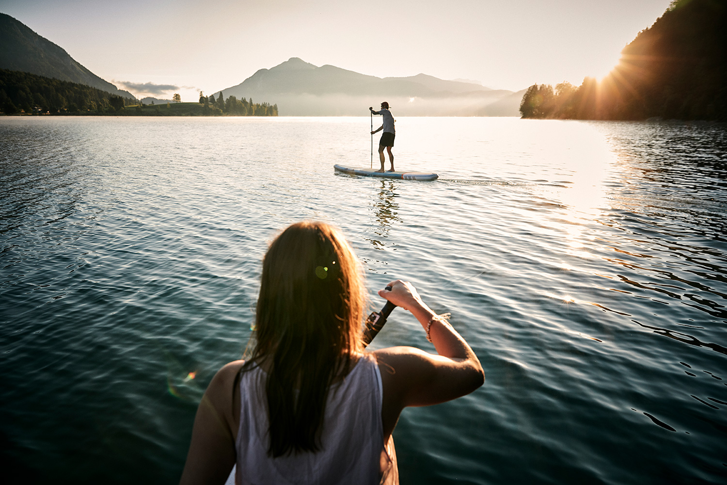 Couple on stand up paddles in the sunrise at Walchensee