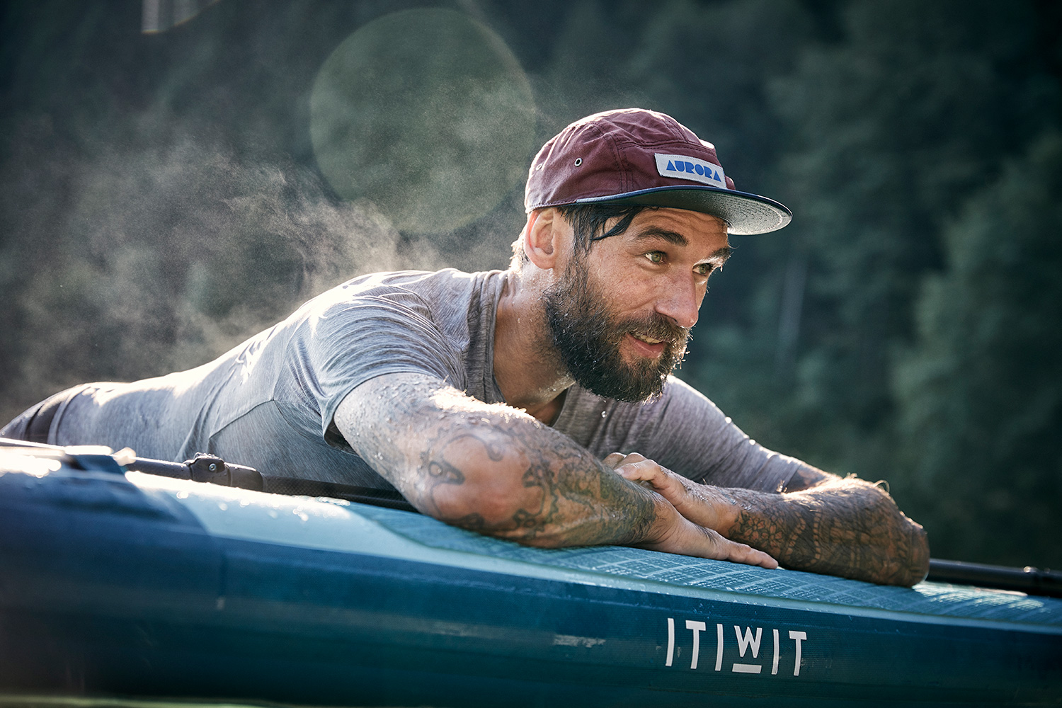 Outdoor sports model Danny lying on a stand up paddle and steaming in the sunrise