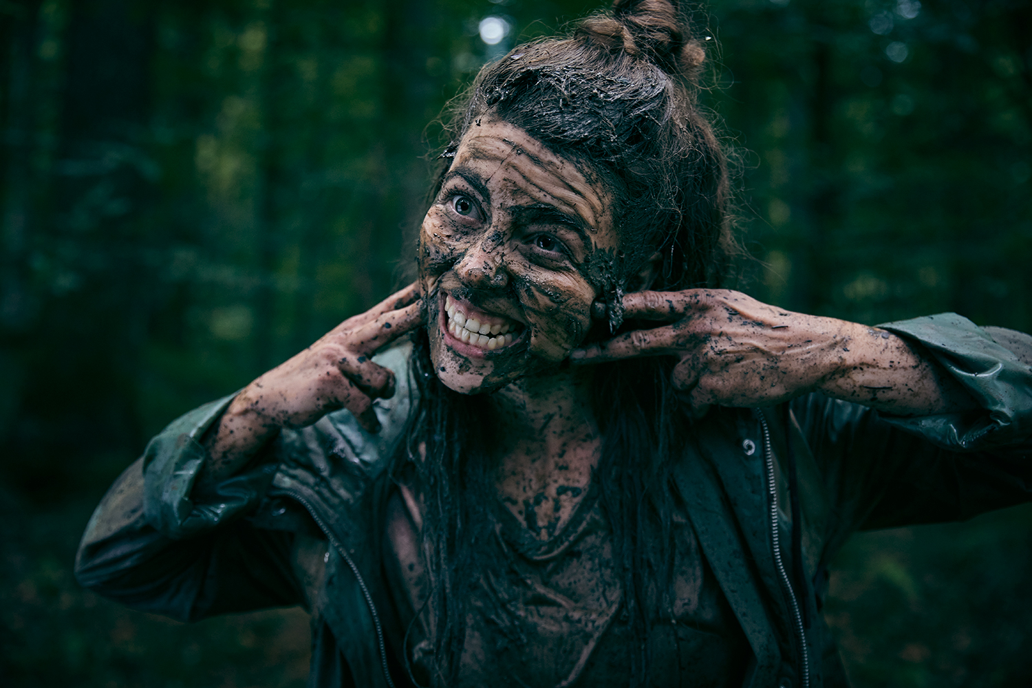 Woman making a scary face having bathed in mud