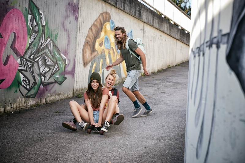 Three friends longboarding with graffiti in the background for TATONKA catalogue Shoot with Jessica Zumpfe