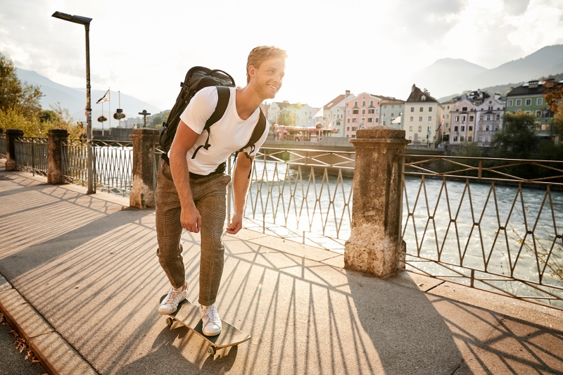 Boy skating along the Inn river across from Mariahilf while the sun sets behind him