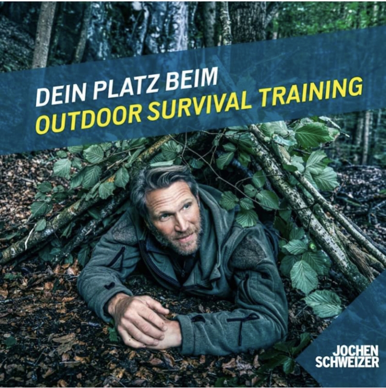 Advertisement for Jochen Schweizer Survival training of a man lying in his homemade shelter in the woods