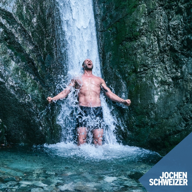 Advertisement for Jochen Schweizer of a man bathing under a freezing cold waterfall and screaming for joy