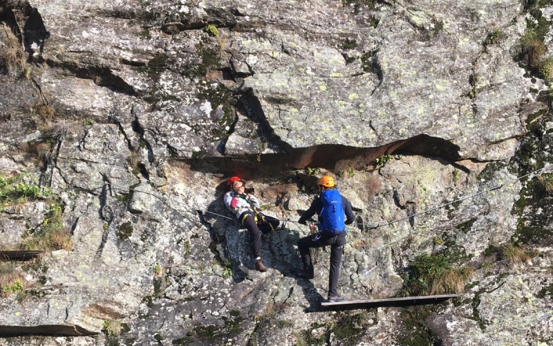 Jessica Zumpfe crouching on a via Ferrata while shooting for the TATONKA catalogue