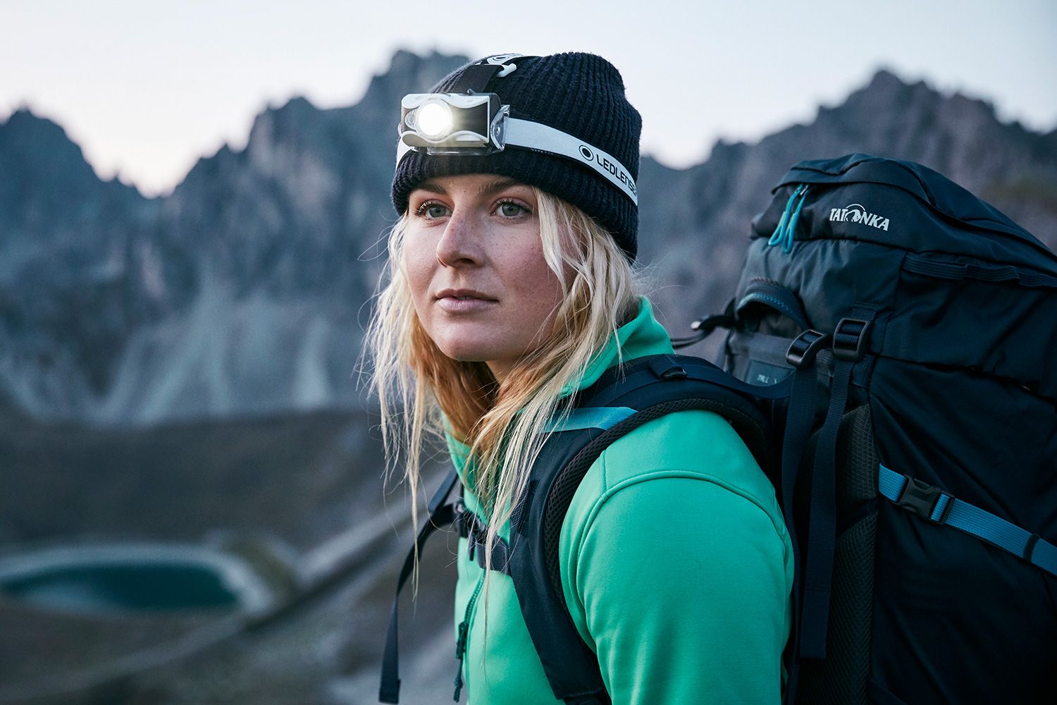 Close-up of a womans face wearing a headlamp ontop of Axamer Lizum before dawn