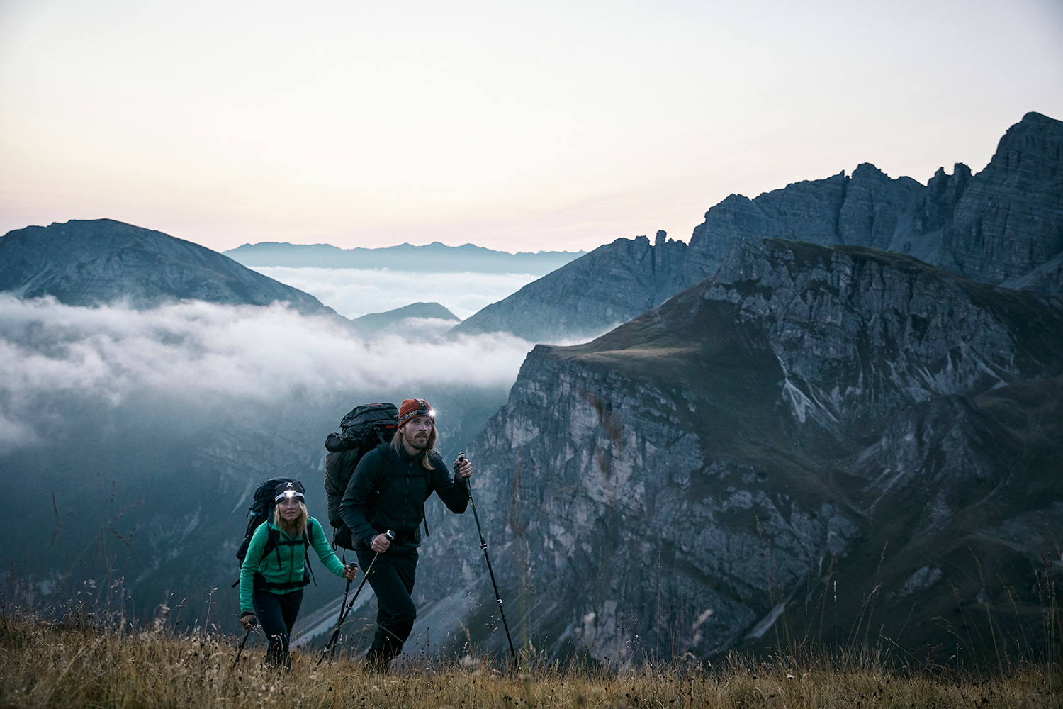 A couple hiking up to the summit before dawn, wearing their headlamps