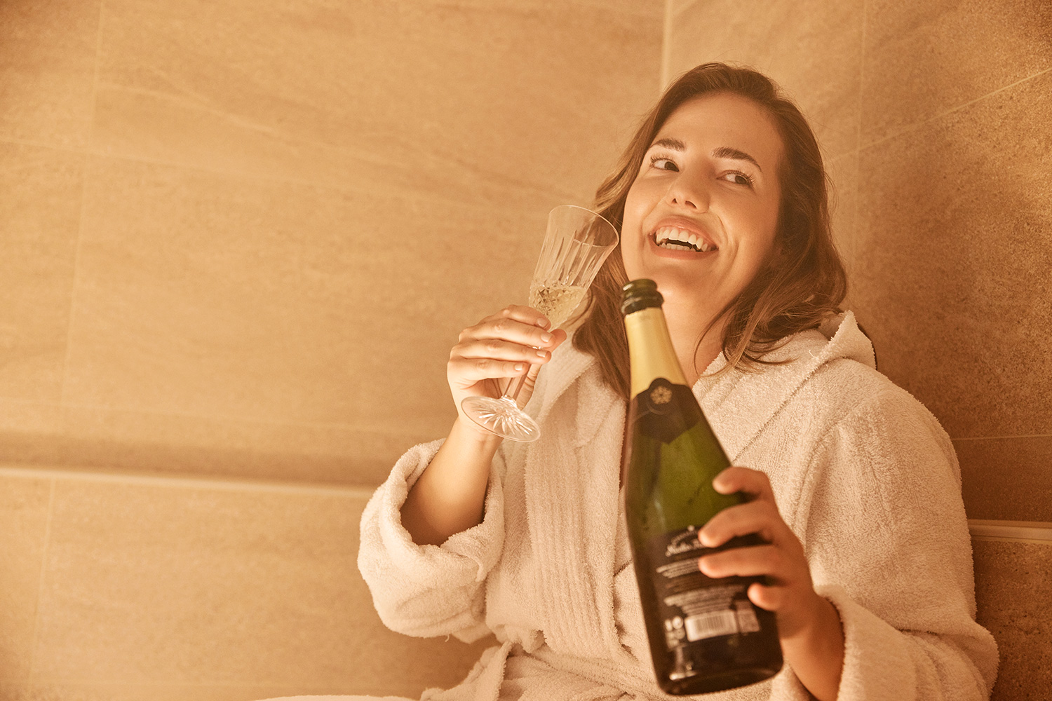 Woman drinking Champagne in a Spa whilst wearing a robe
