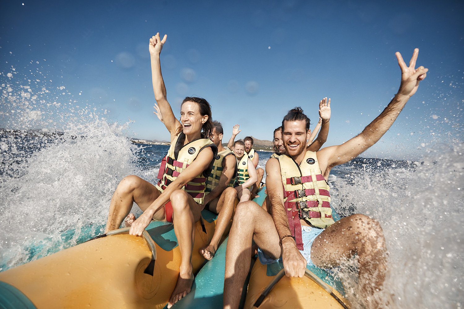 Couple riding a banana boat with their friends