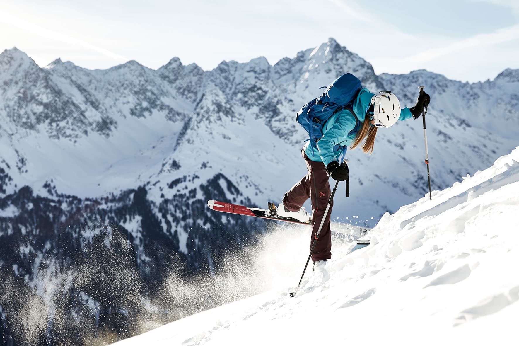 Julia turning her Ski's on a steep climb on our skitour in the mountains near Innsbruck. The snow spraying behind her, and the mountains in the background.