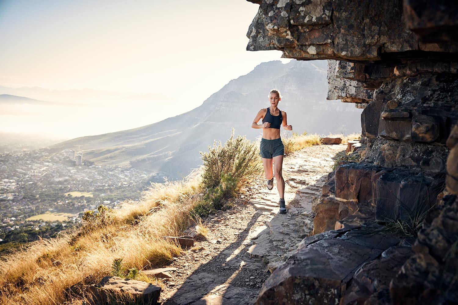 Young Woman trailrunning on Table Mountain along the rocks