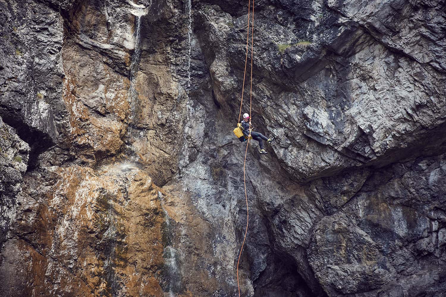 Stunt Woman Kim abseiling down a very high cliff on a canyoning tour in Austria