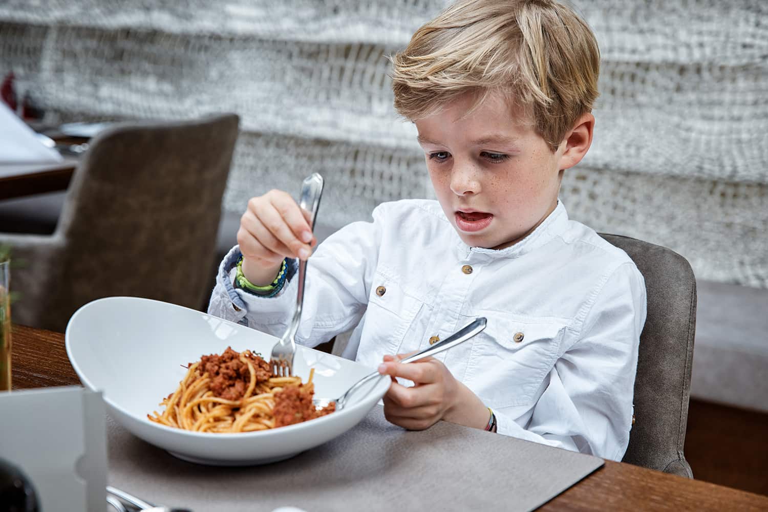Young boy eating spaghetti in a hotel restaurant