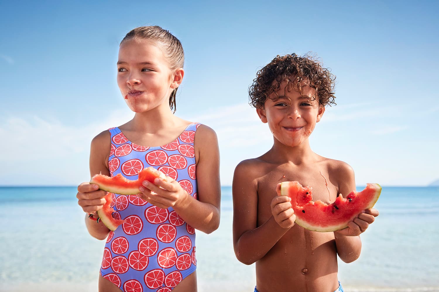 Girl and Boy enjoying their watermelon on a beach in Mallorca