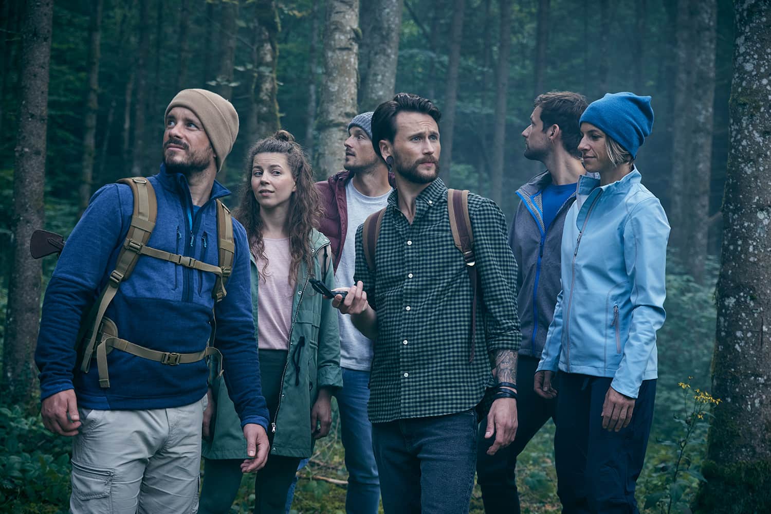 Five friends in the woods navigating with a compass