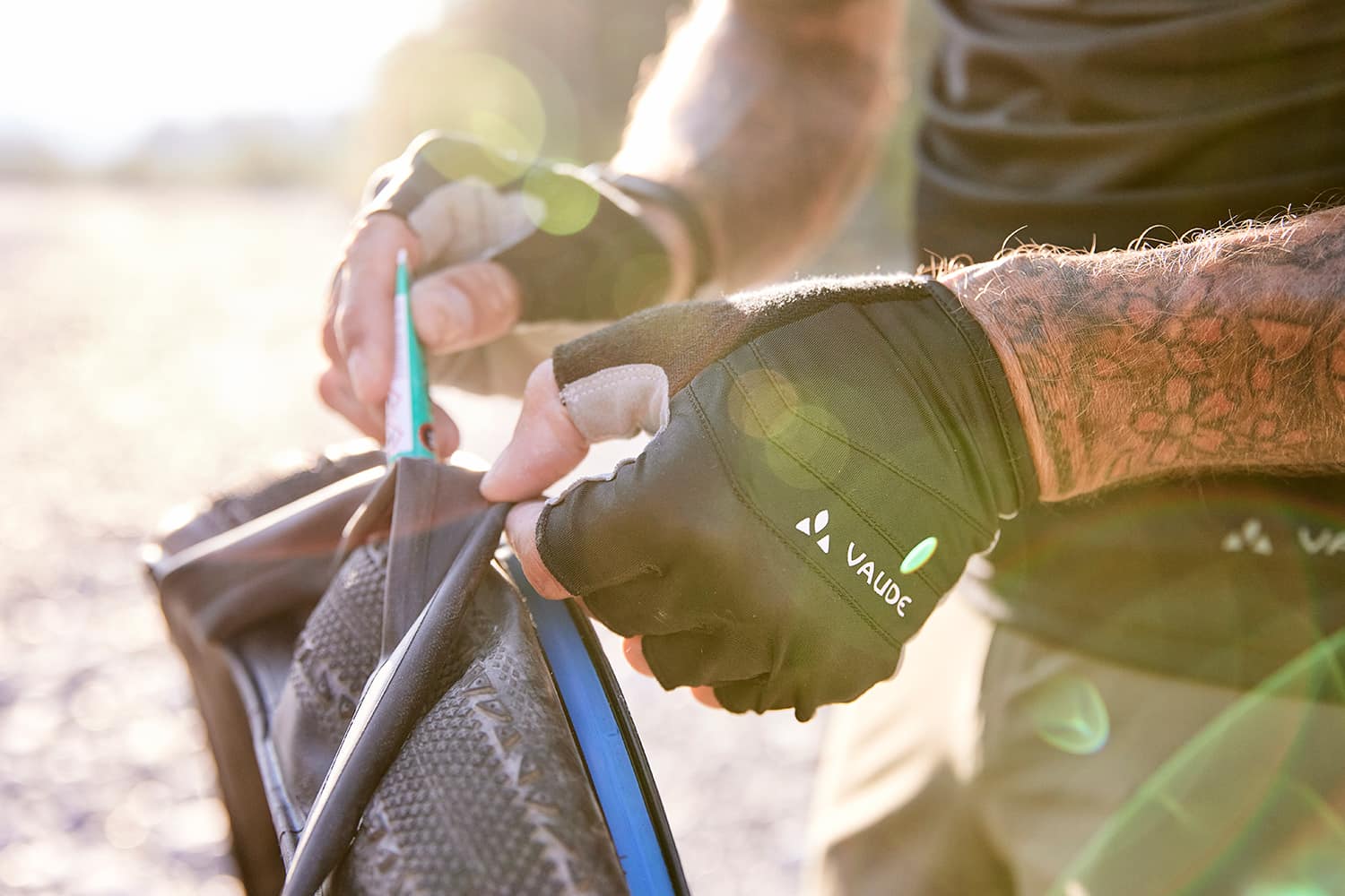 Detail of a man fixing a bicycle tire wearing VAUDE gloves
