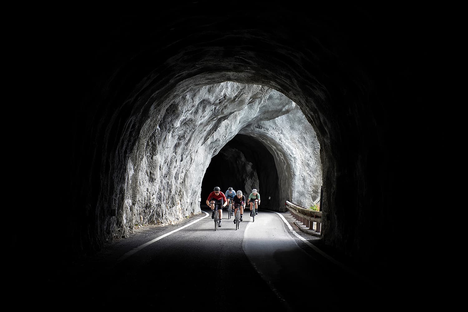 Four road cyclists cycling through a tunnel