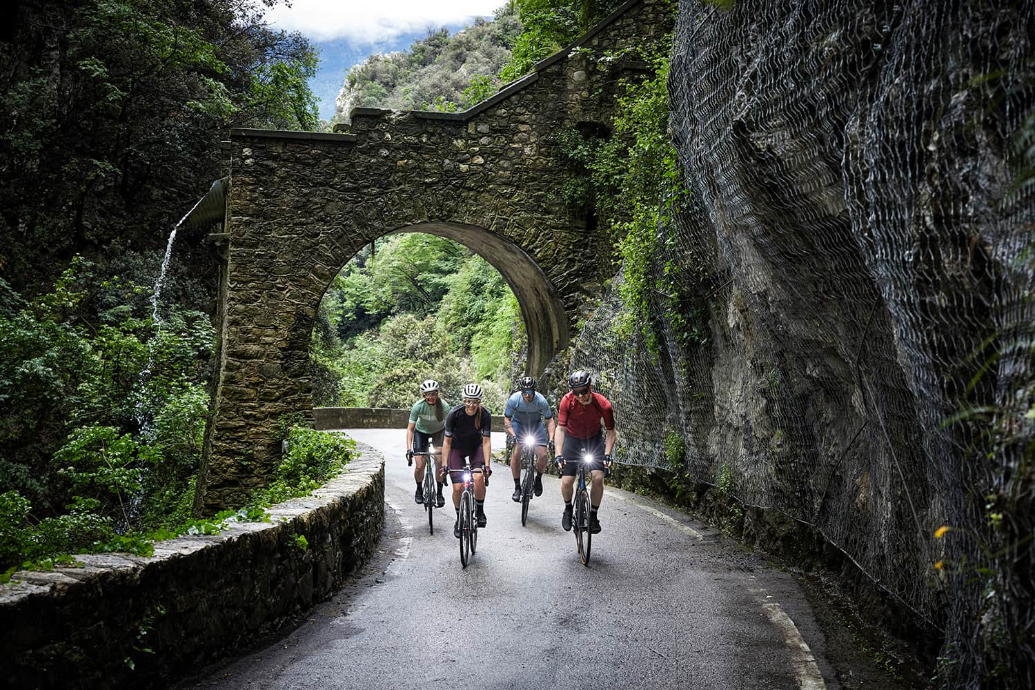 Four road cyclists riding through the Strada della Forra at Lake Garda